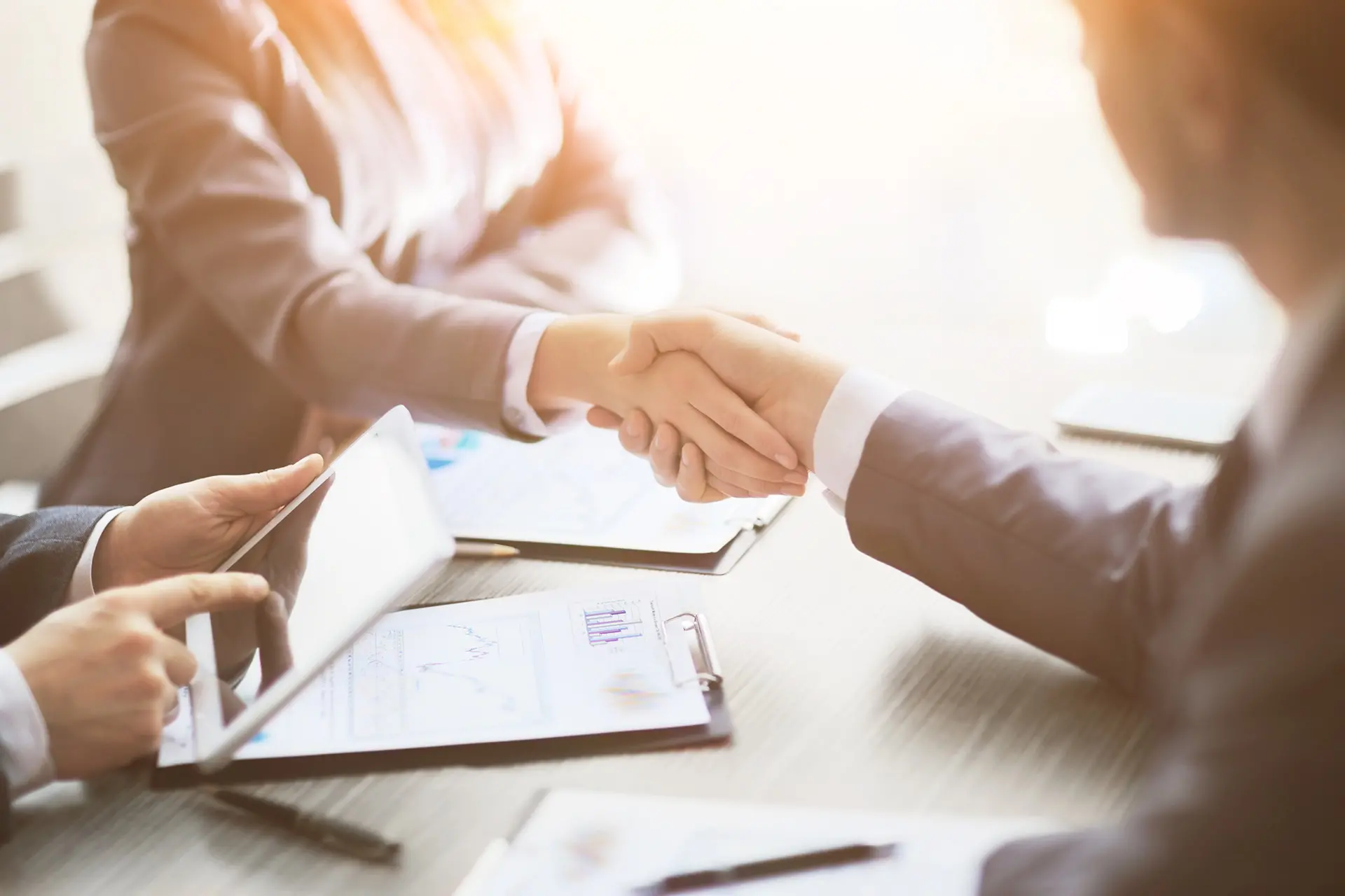 Leerink Partners Transactions, two corporate executives shaking hands across the conference table after closing a deal